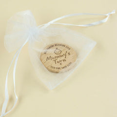 Wooden coin with 'Mummy's Turn' text in a sheer bag on a beige background