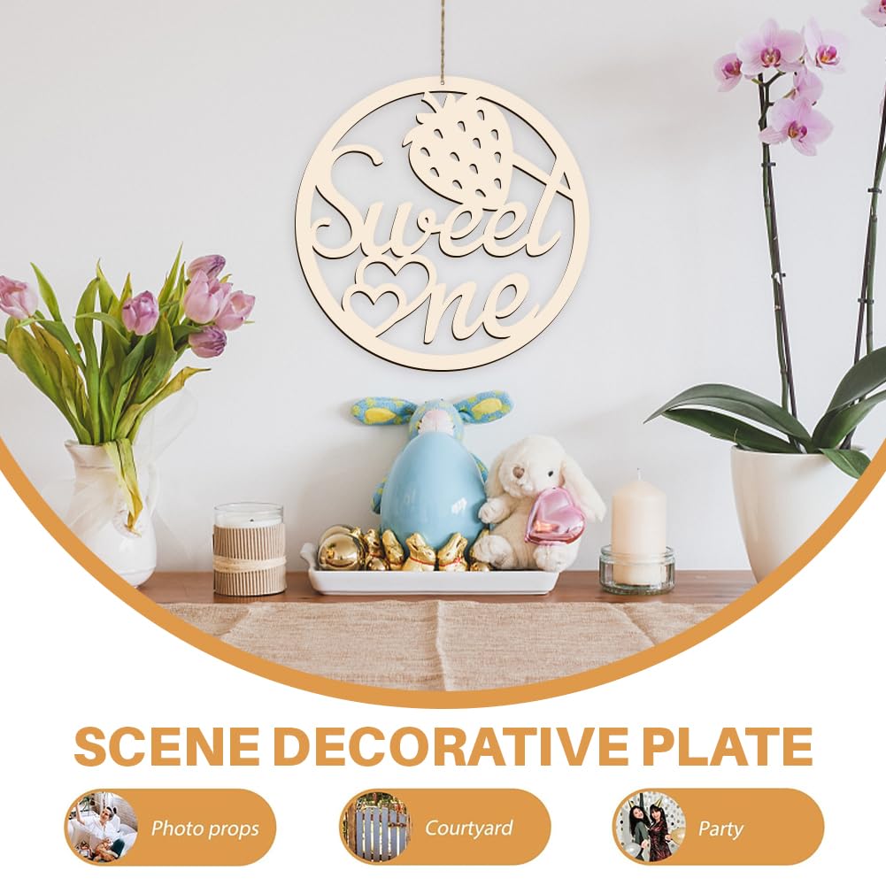 Decorative plate with 'Sweet One' text, surrounded by flowers and small toys on a wooden surface.