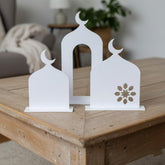 Decorative white metal bookends with crescent moon design on a wooden surface.