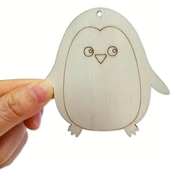 Wooden penguin ornament held by a hand on a white background