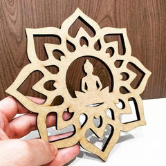 Decorative wooden cutout with Buddha silhouette in a mandala design held by a hand against a wooden background.
