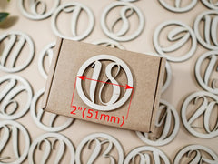 Wooden number '18' on a cardboard box with measurements, surrounded by similar wooden numbers.