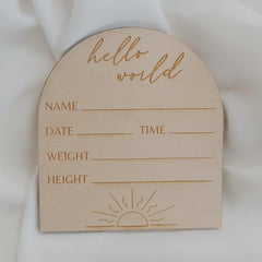 Wooden baby milestone card with 'hello world' text and blank lines for personalization on a white background.