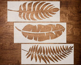 Three leaf-shaped stencils on a wooden surface
