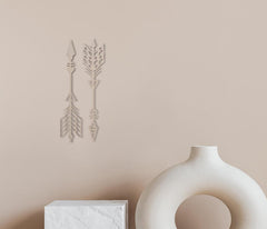Decorative wall stickers of arrows on a beige wall with a white vase and box in the foreground.