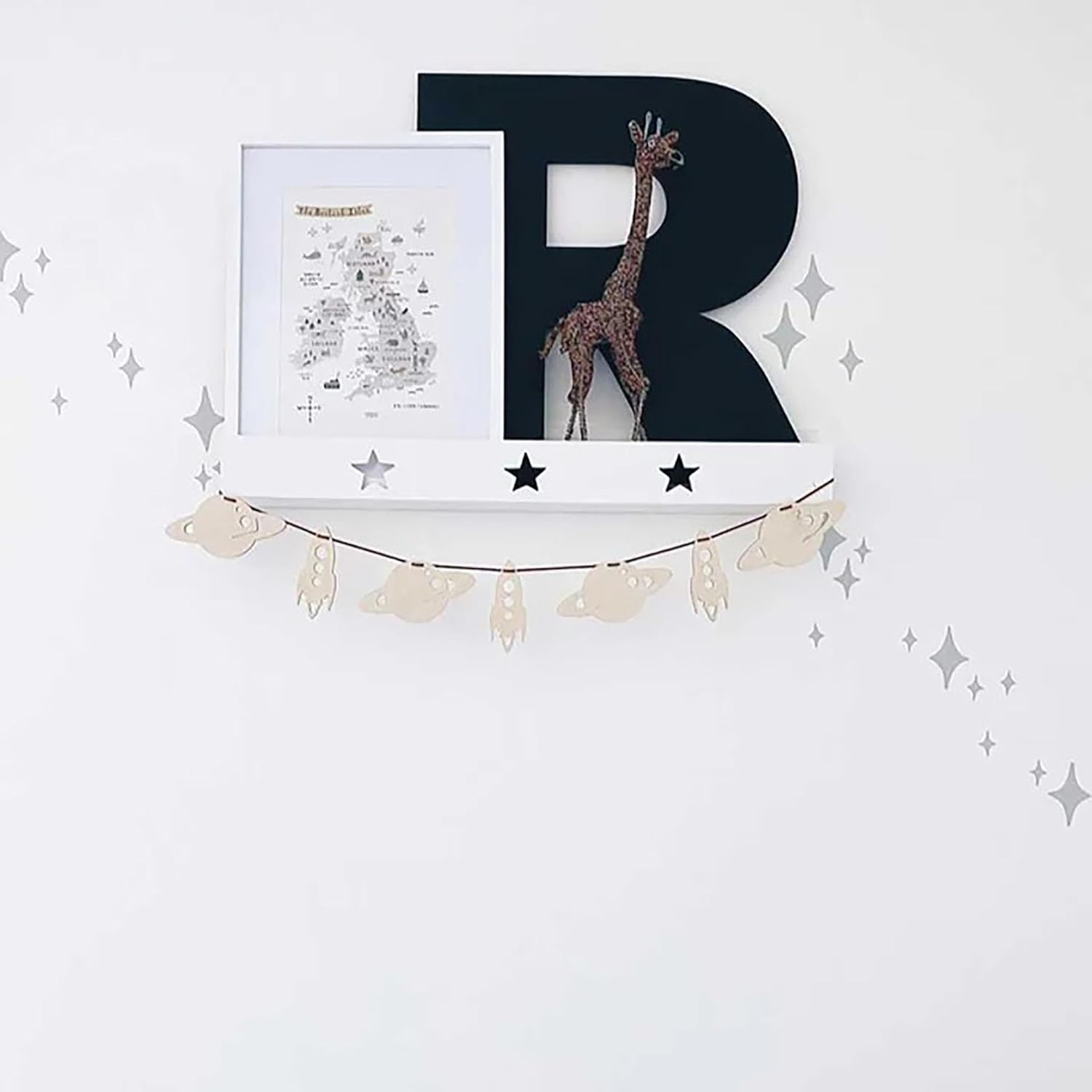 Decorative letter 'R' with a giraffe illustration on a white wall with star patterns.