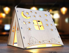 Decorative night light shaped like a house with stars and moon on a wooden surface.