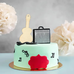 Cake with guitar and amplifier topper on a light blue background