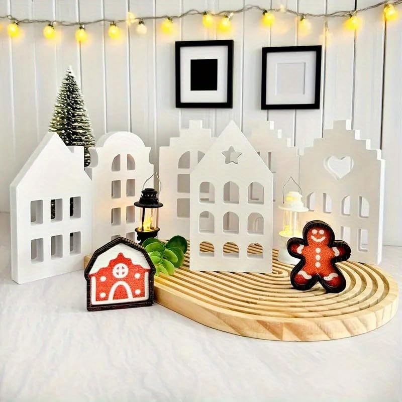 Decorative set with white houses, gingerbread man, and lantern on a wooden base with string lights in the background.