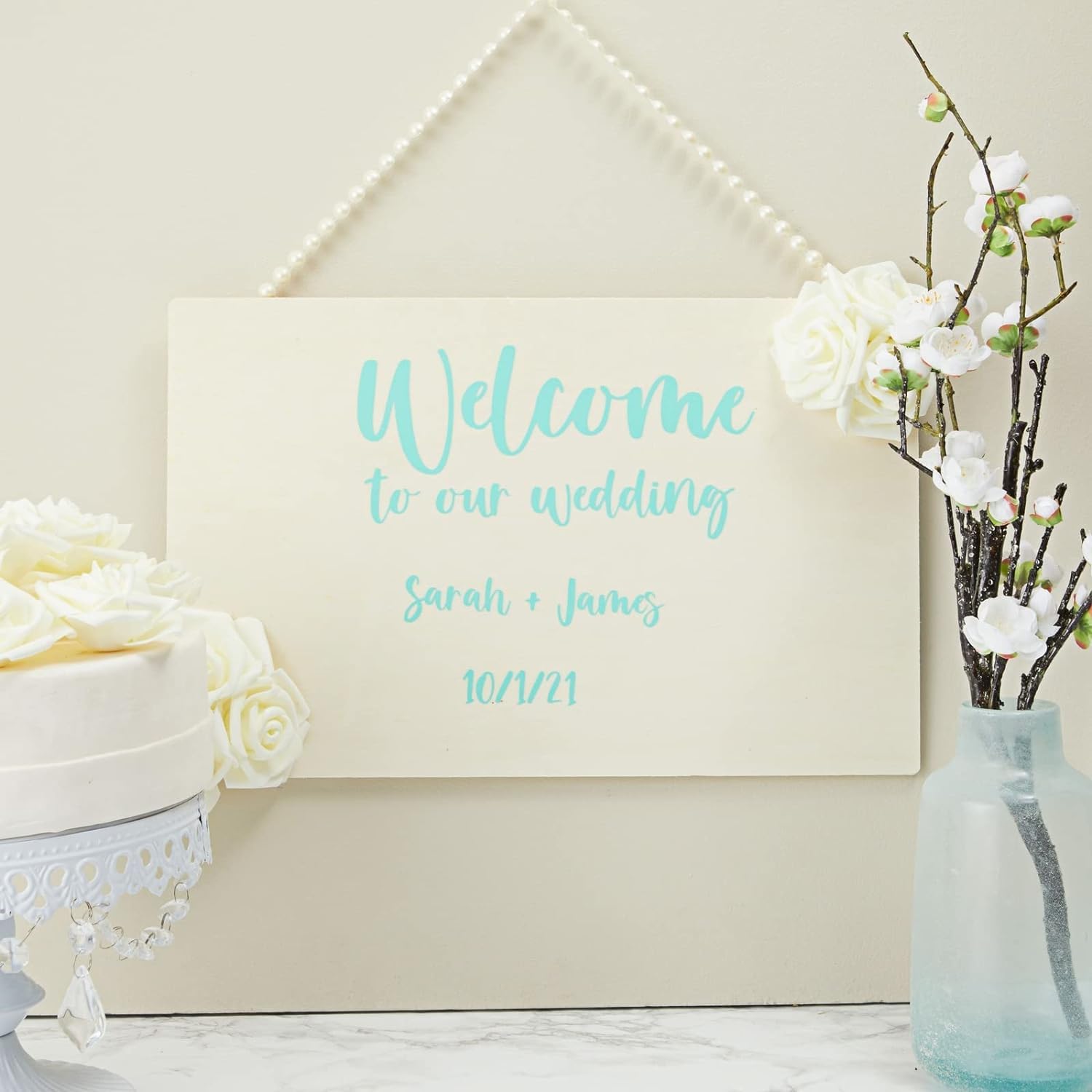Wedding welcome sign with floral decorations on a white surface