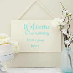 Wedding welcome sign with floral decorations on a white surface