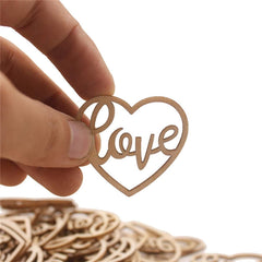 Heart-shaped wooden cutout with 'love' text held by a hand against a white background
