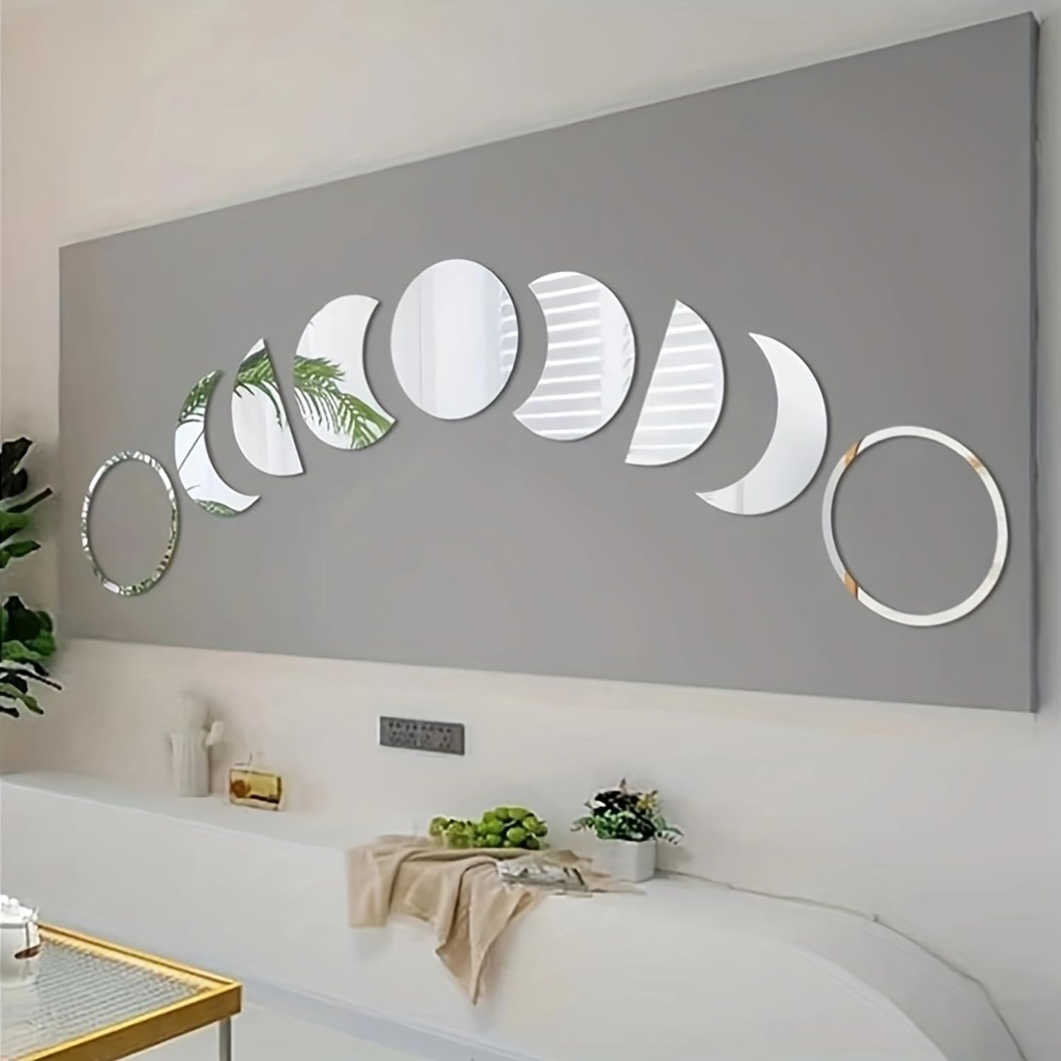 Decorative wall art with moon phases on a gray wall above a white couch.