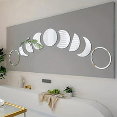 Decorative wall art with moon phases on a gray wall above a white couch.
