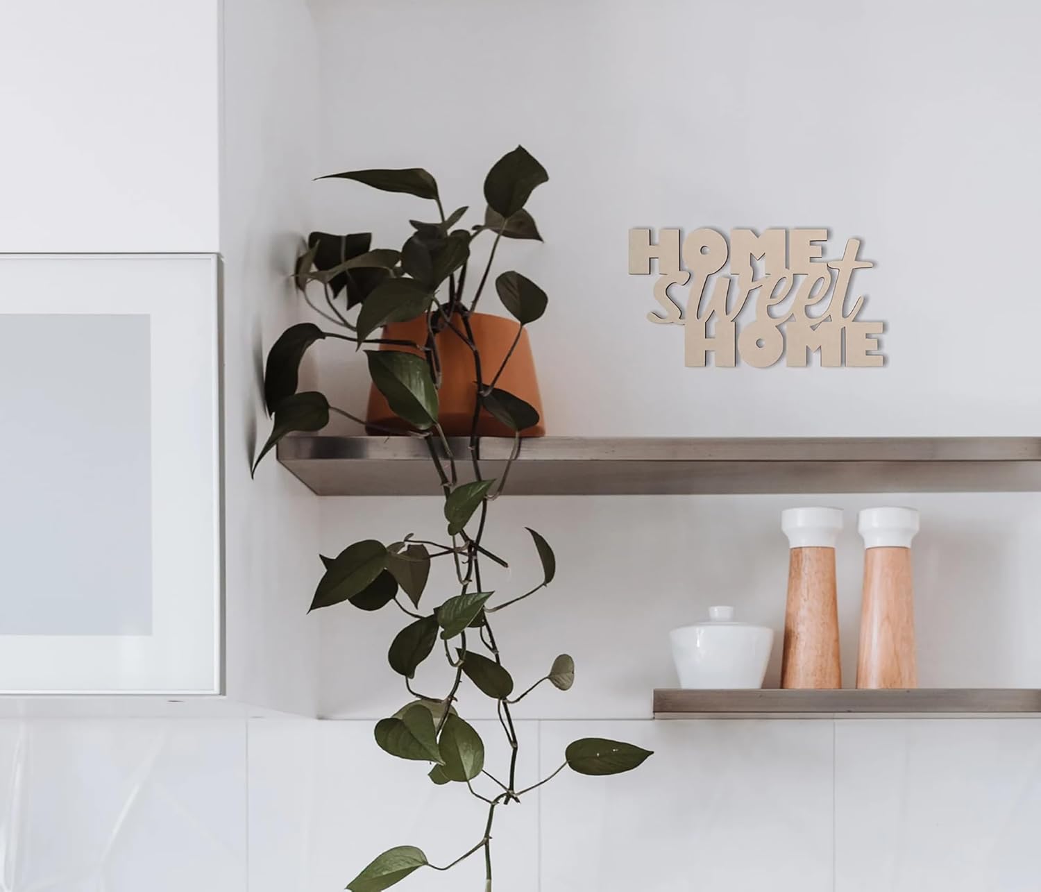 Home sweet home decorative sign on a shelf with a plant in the foreground