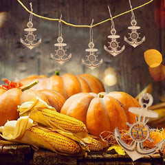 Decorative arrangement with pumpkins, corn, and nautical-themed ornaments on a wooden surface.
