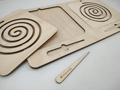 Wooden laser-cut cutting boards with spiral patterns and a knife on a light gray background