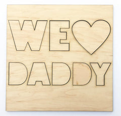 Wooden cutout with 'WE LOVE DADDY' text on a white background