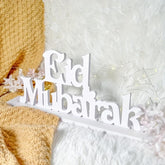 White 'Eid Mubarak' sign on a textured white and yellow background