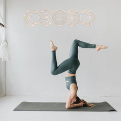 Person in green leggings performing a yoga pose on a mat with decorative elements above.