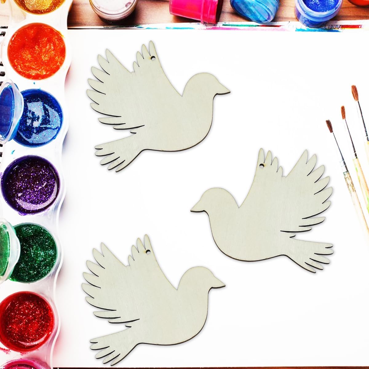White dove shapes with paint and brushes on a wooden surface