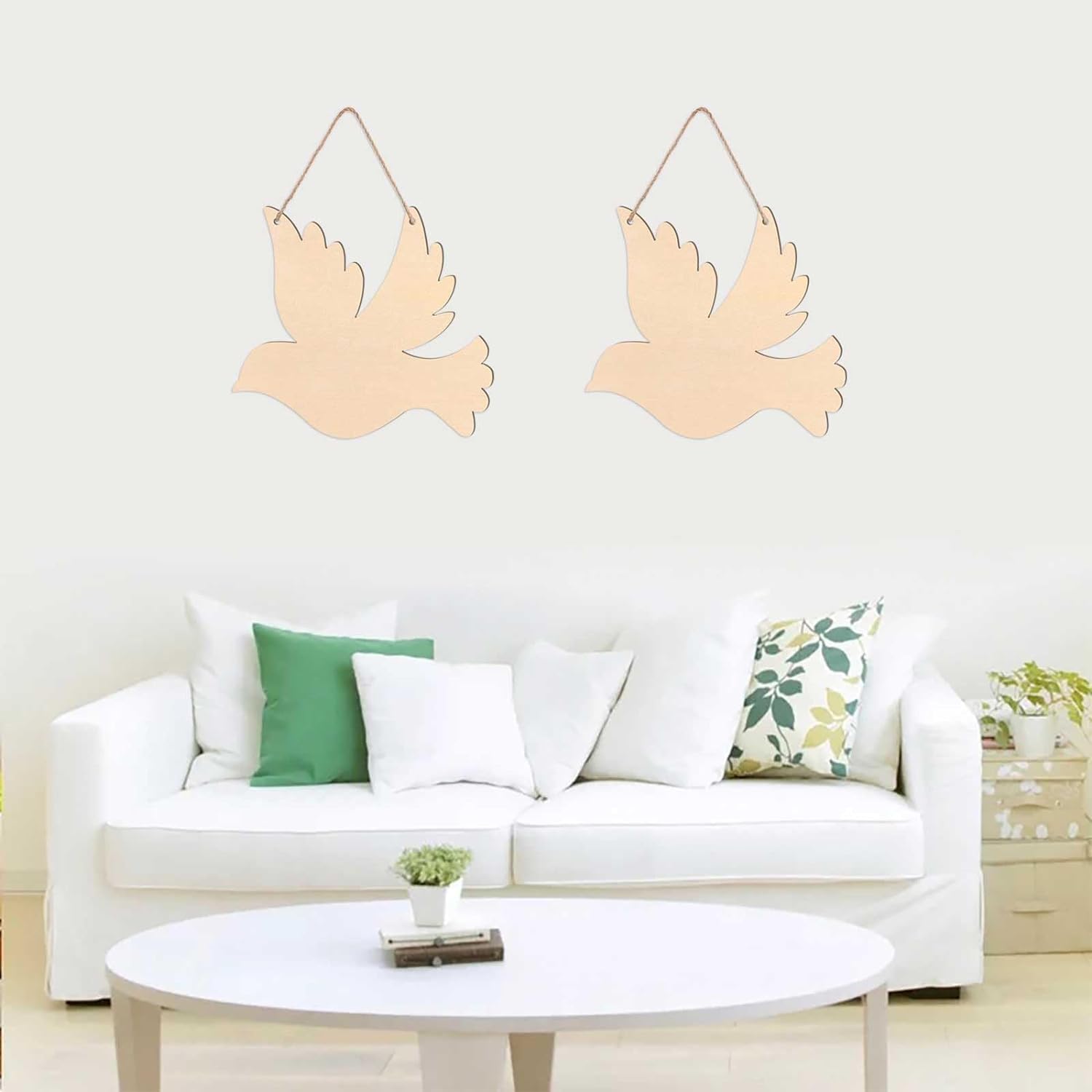 Two wooden dove decorations hanging above a white sofa with green and patterned cushions.