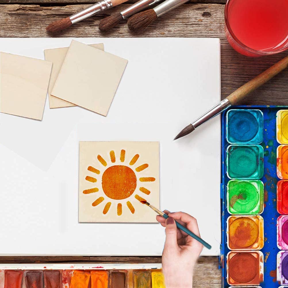 Person painting a sun design on paper with watercolor paints and brushes.