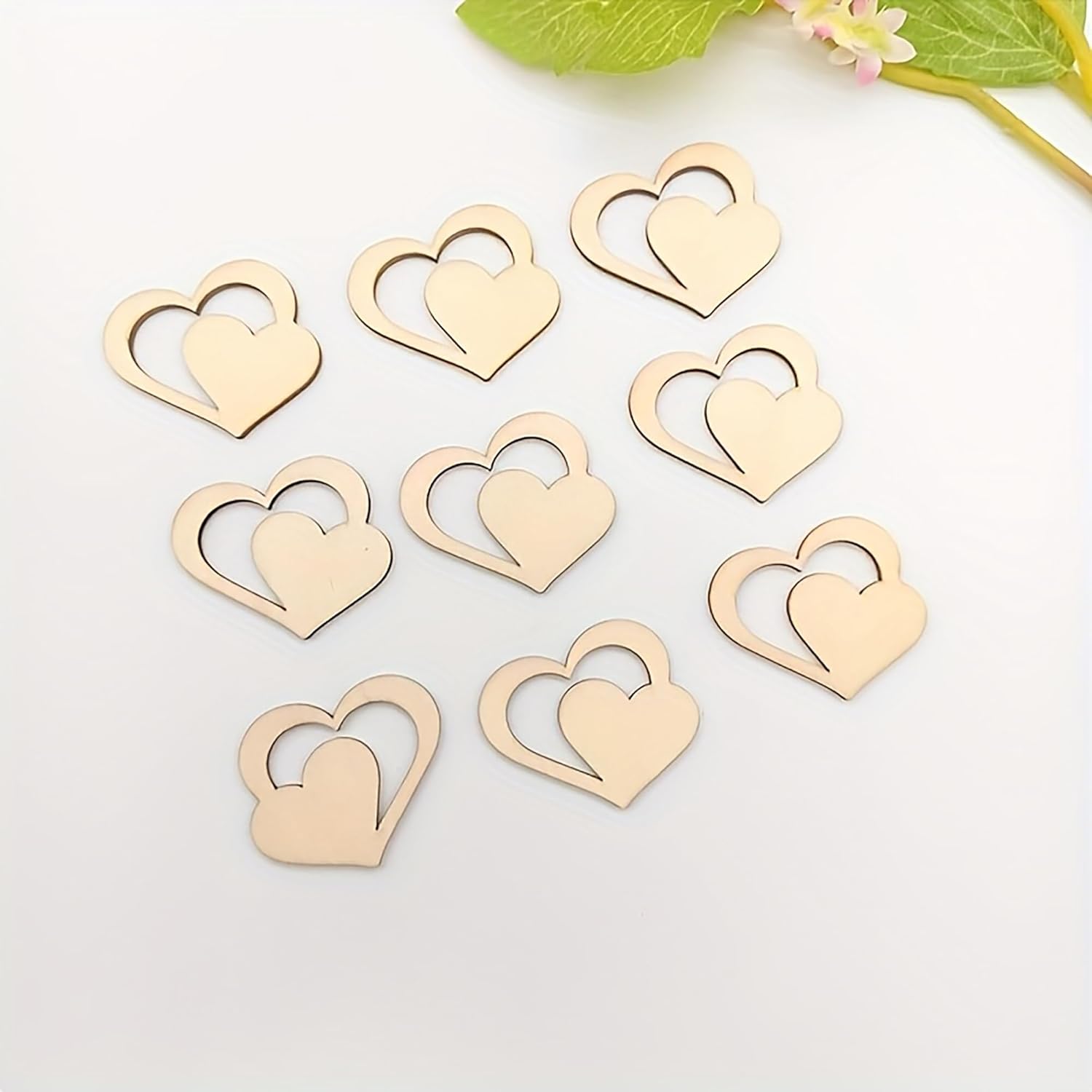 Gold heart-shaped objects on a white surface with green leaves in the background