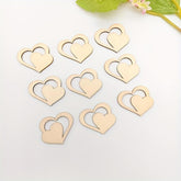 Gold heart-shaped objects on a white surface with green leaves in the background