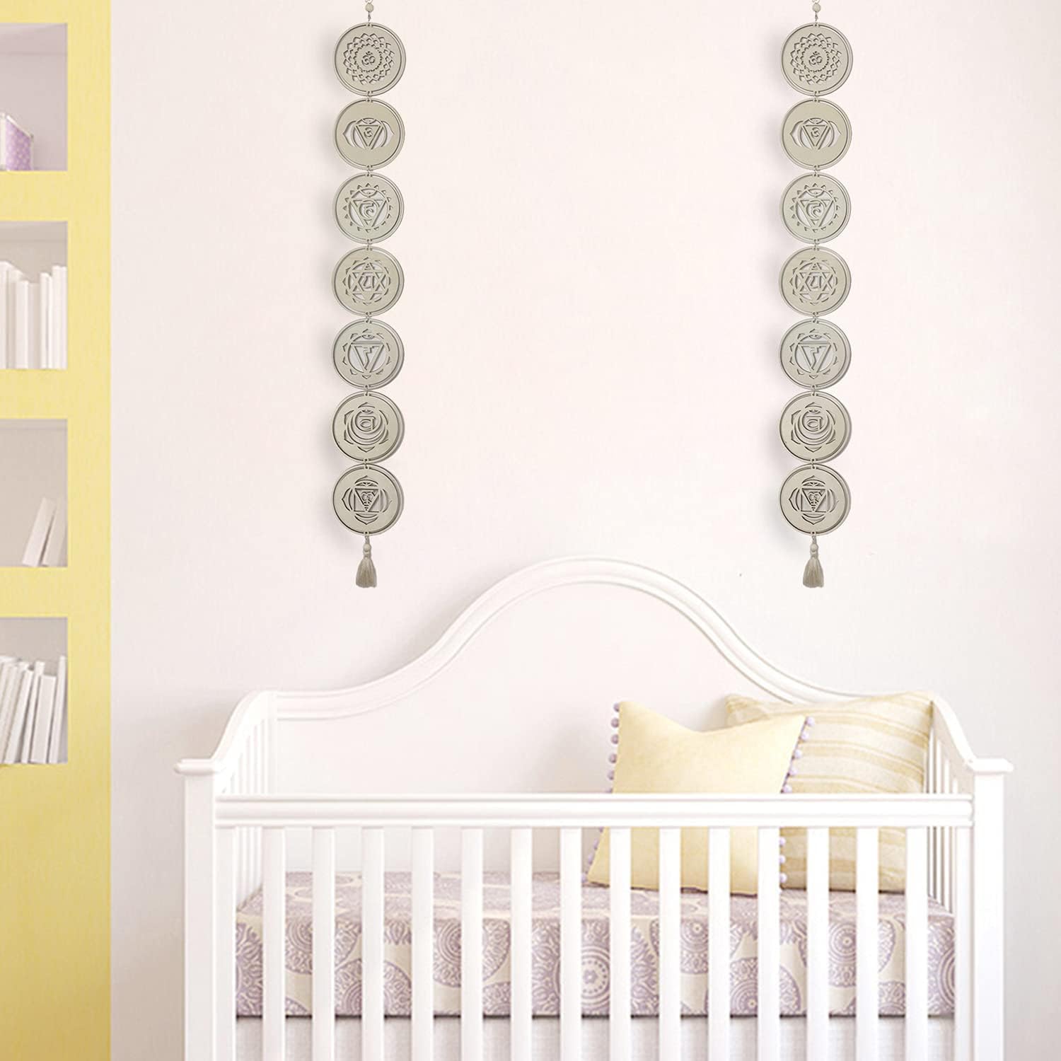 Nursery room with a white crib, yellow pillow, and decorative wall hanging.