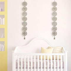 Nursery room with a white crib, yellow pillow, and decorative wall hanging.