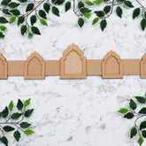 Decorative cardboard arches on a marble surface with green leafy branches.