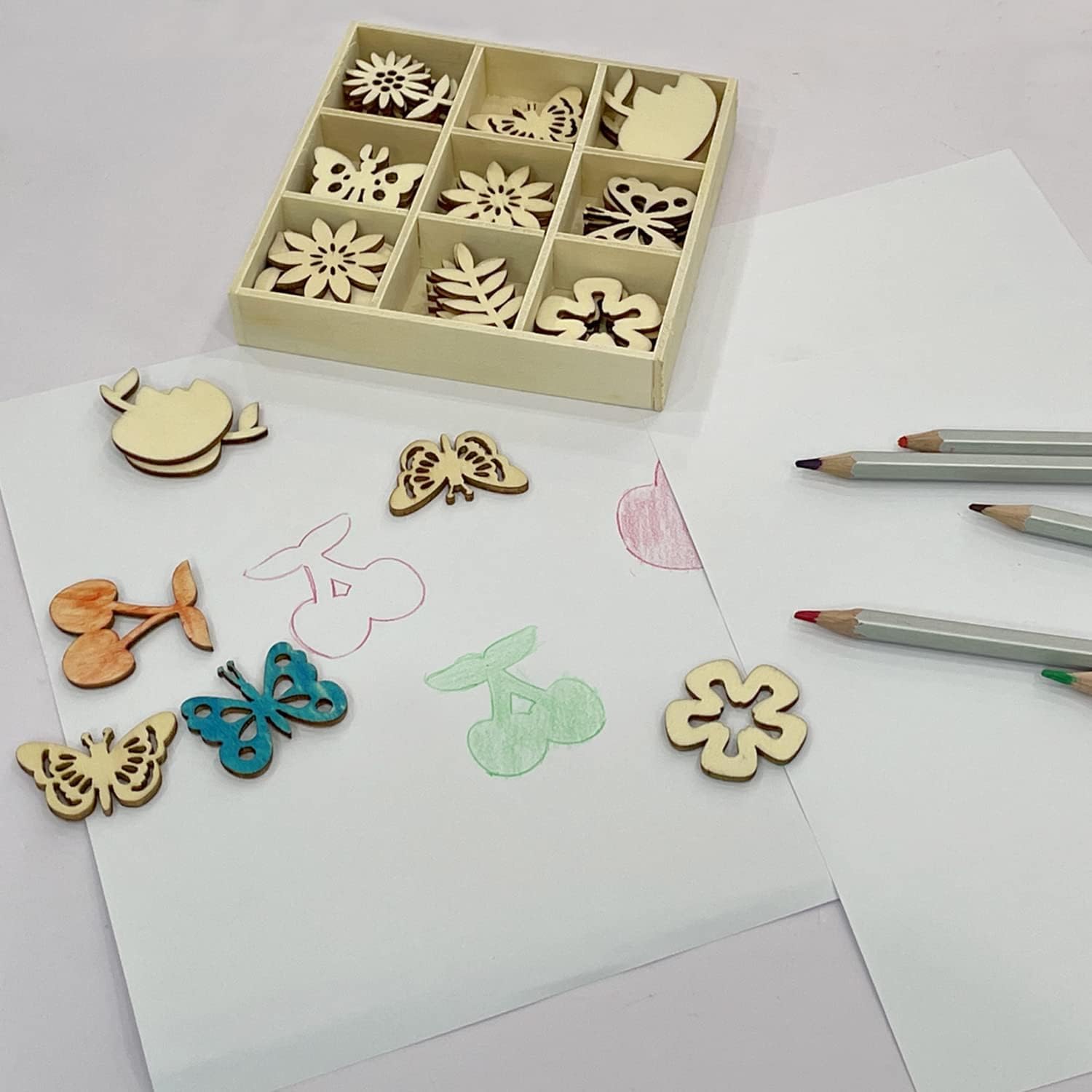 Wooden stamps with floral and butterfly designs on a white surface with colored pencils.