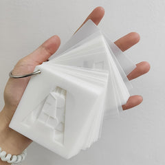 Hand holding a stack of white cards with cut-out shapes on a light gray background