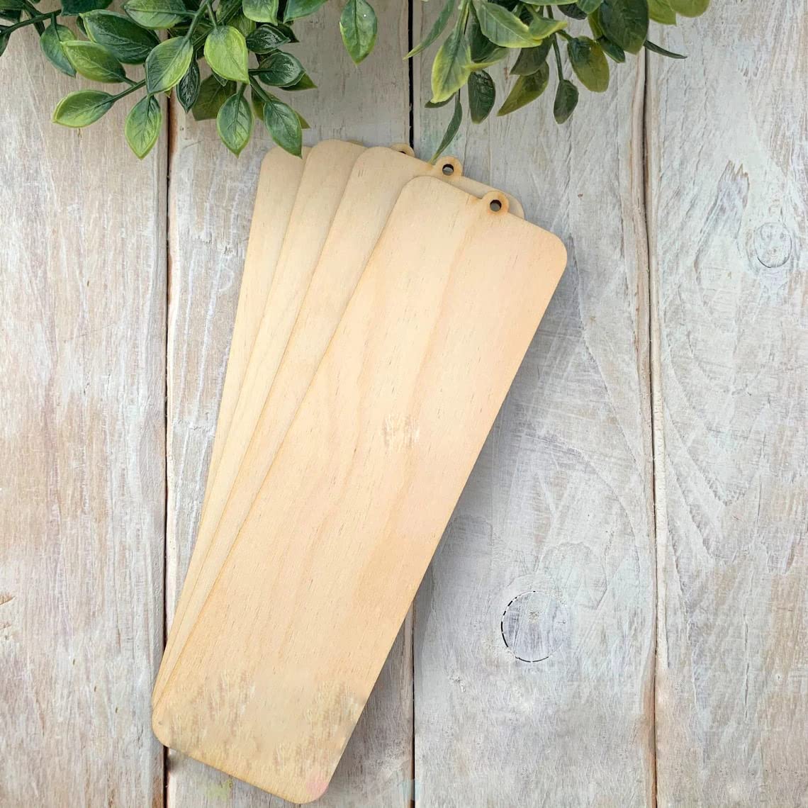 Three wooden cutting boards on a rustic wooden surface with greenery above.