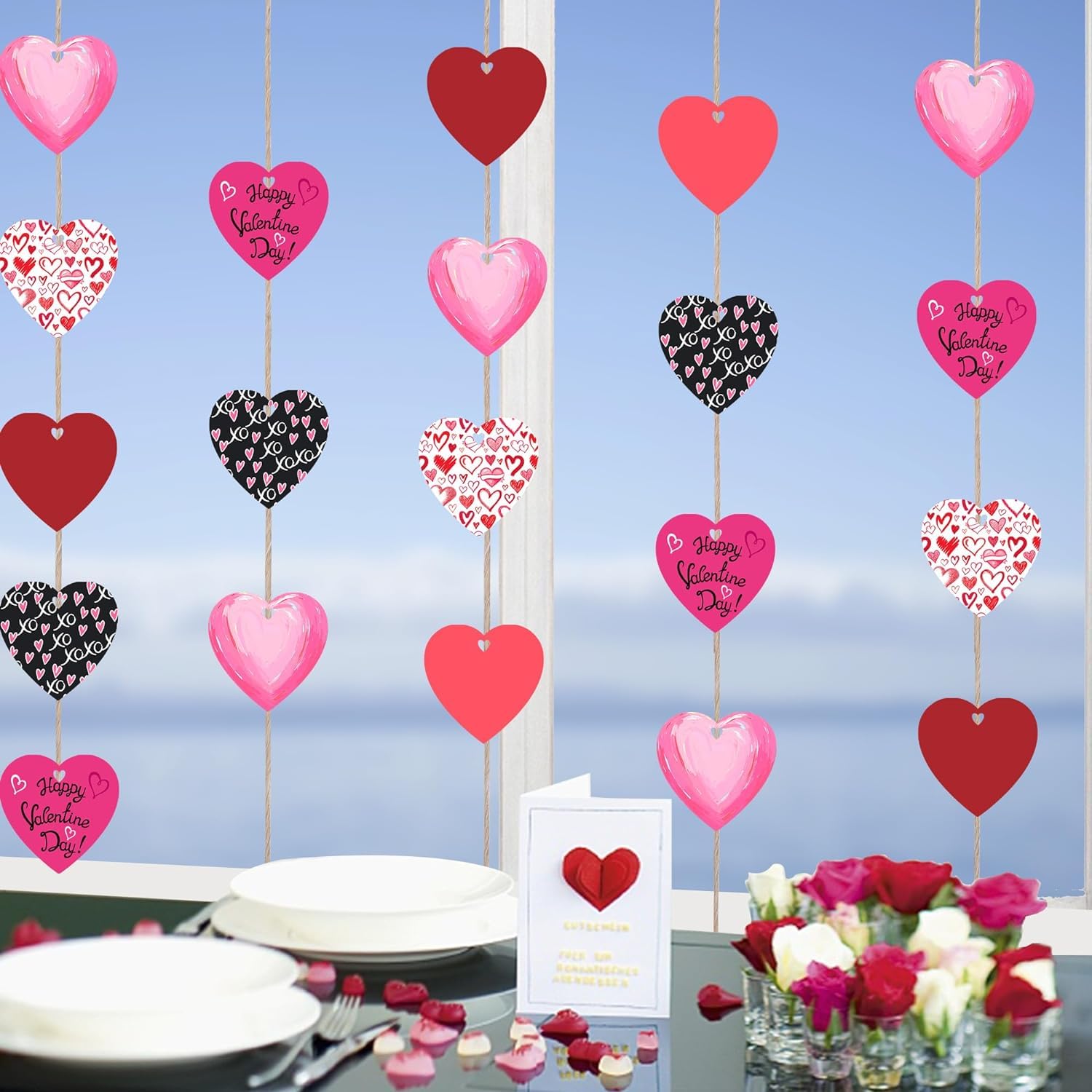 Valentine's Day decorations with heart-shaped balloons and a card on a table with flowers and plates.