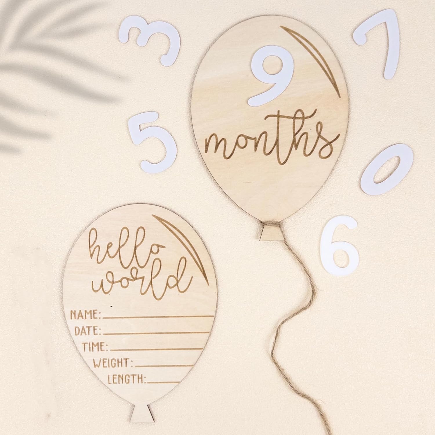 Wooden balloon-shaped milestone markers with numbers and text on a beige background