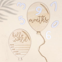 Wooden balloon-shaped milestone markers with numbers and text on a beige background
