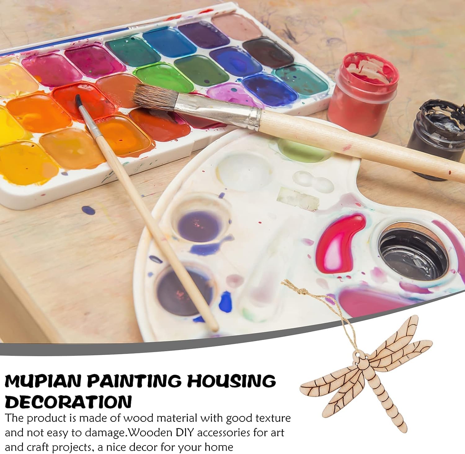 Painting supplies including a paint palette, brushes, and wooden dragonfly decoration on a wooden surface.