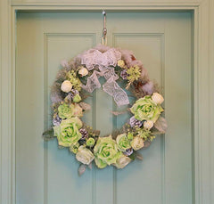 Floral wreath with green and white flowers on a light blue door