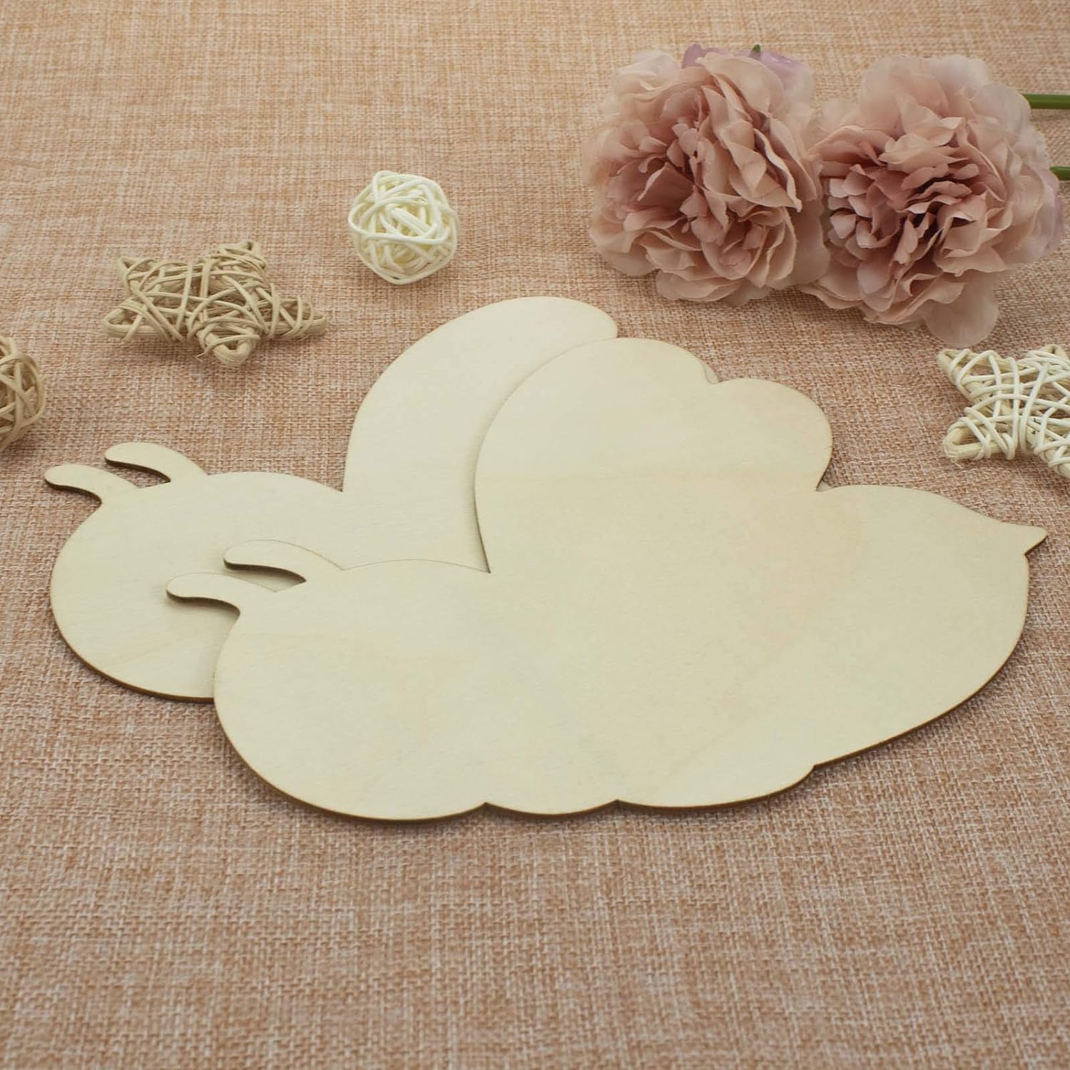 Wooden cloud-shaped decorative item on a textured fabric background with flowers and decorative elements.