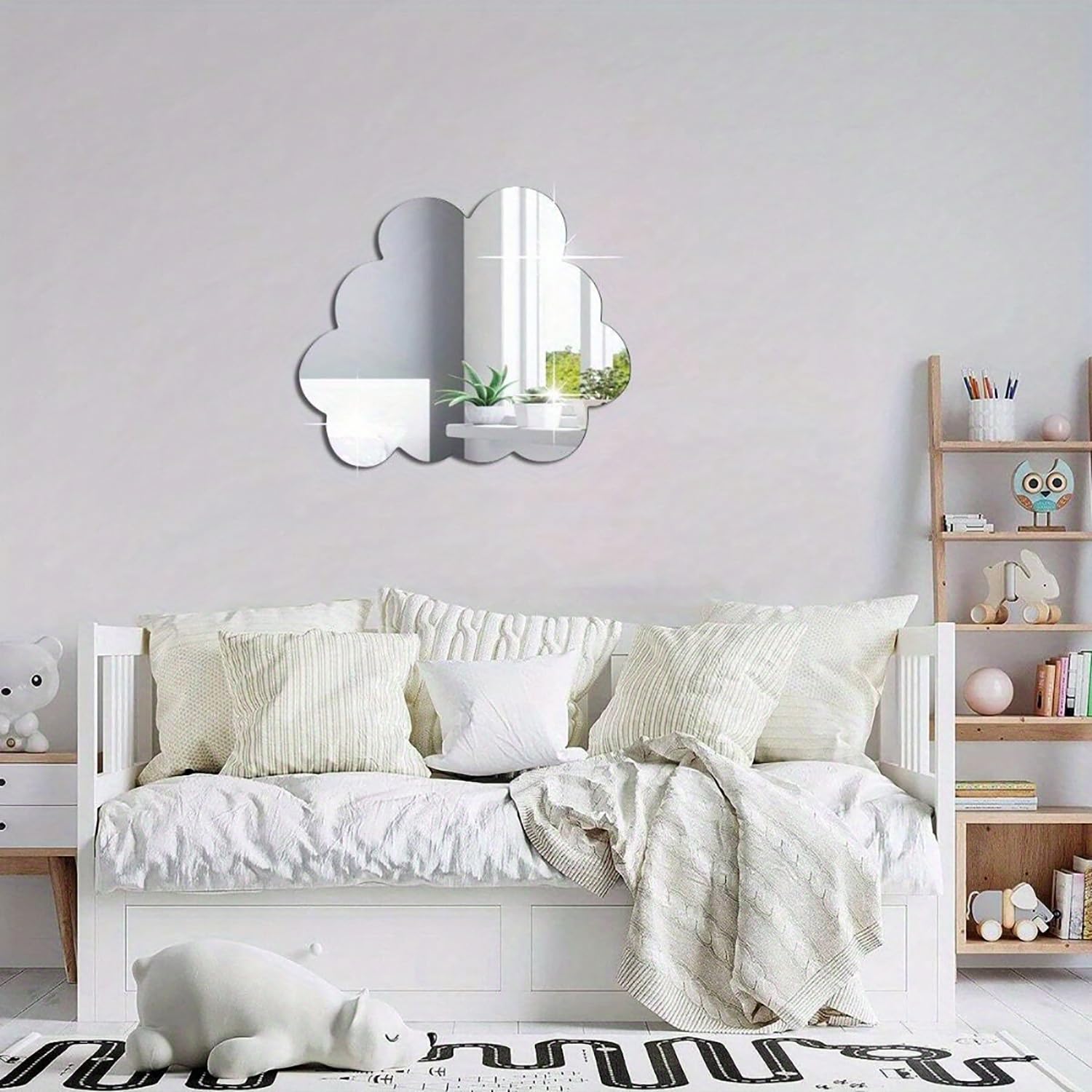 Children's bedroom with a white bed, cloud-shaped mirror, and wooden shelf.