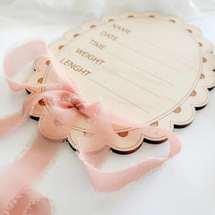 Heart-shaped wooden plaque with text and a pink ribbon on a white background
