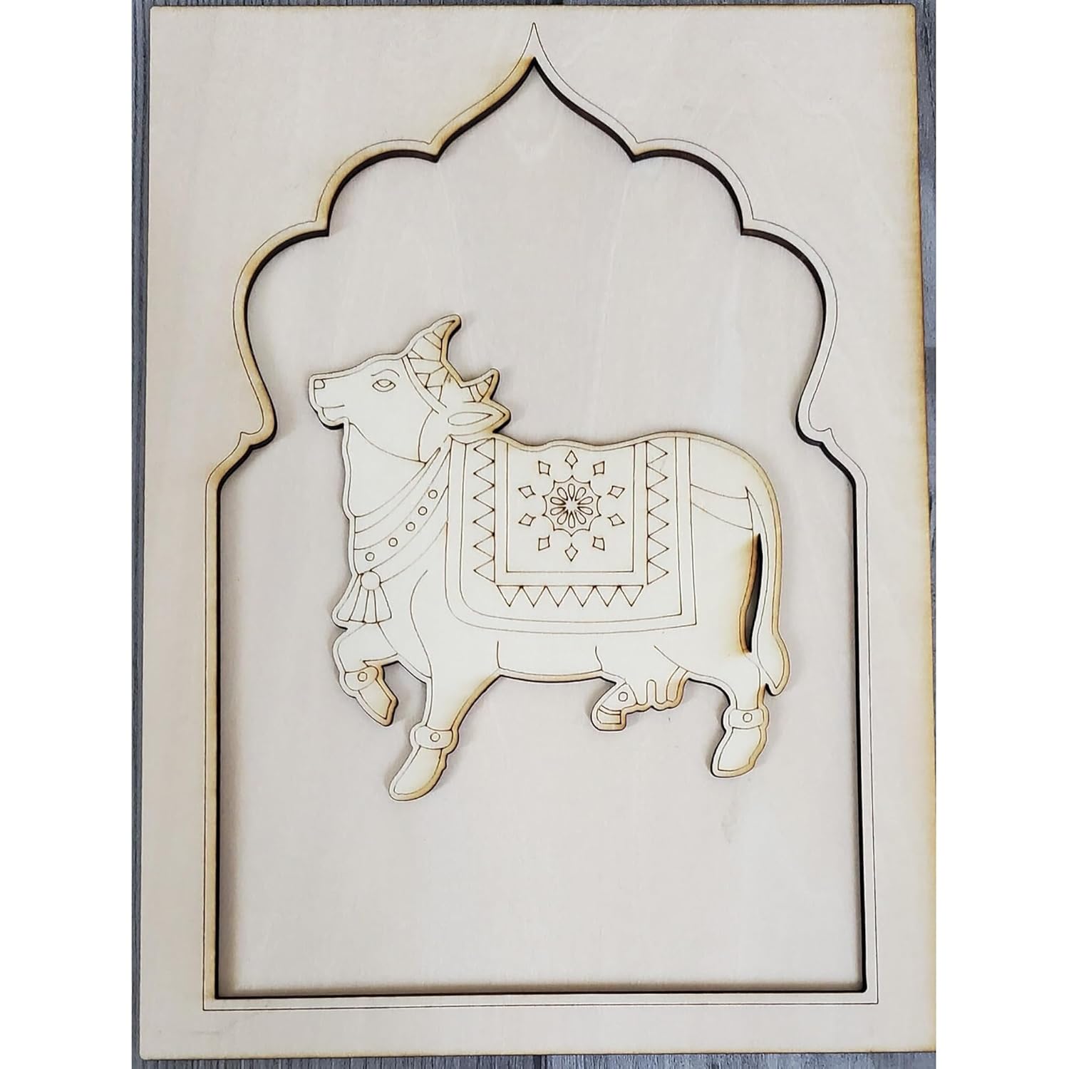 Decorative wall art with a cow design in a decorative frame on a white background