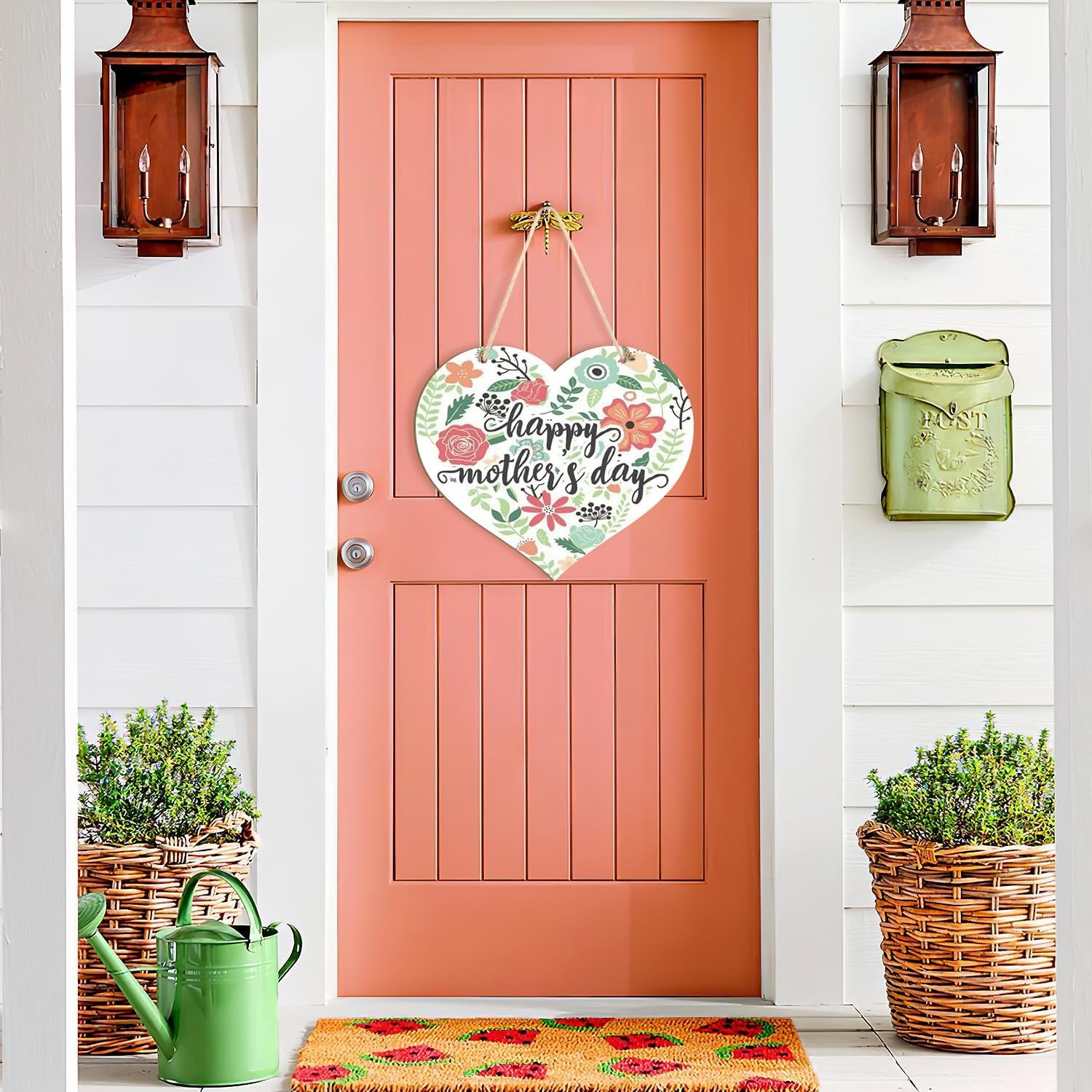 Decorative 'Happy Mother's Day' heart sign on a coral door with plants and a watering can.