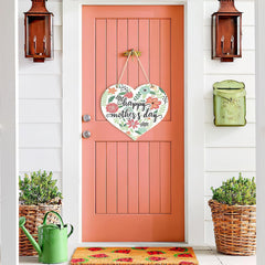 Decorative 'Happy Mother's Day' heart sign on a coral door with plants and a watering can.