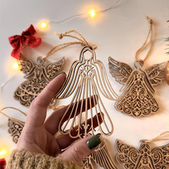 Decorative angel ornament held by a hand with string lights in the background