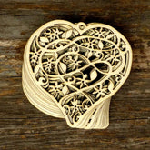 Wooden heart-shaped ornament with intricate cut-out patterns on a wooden surface