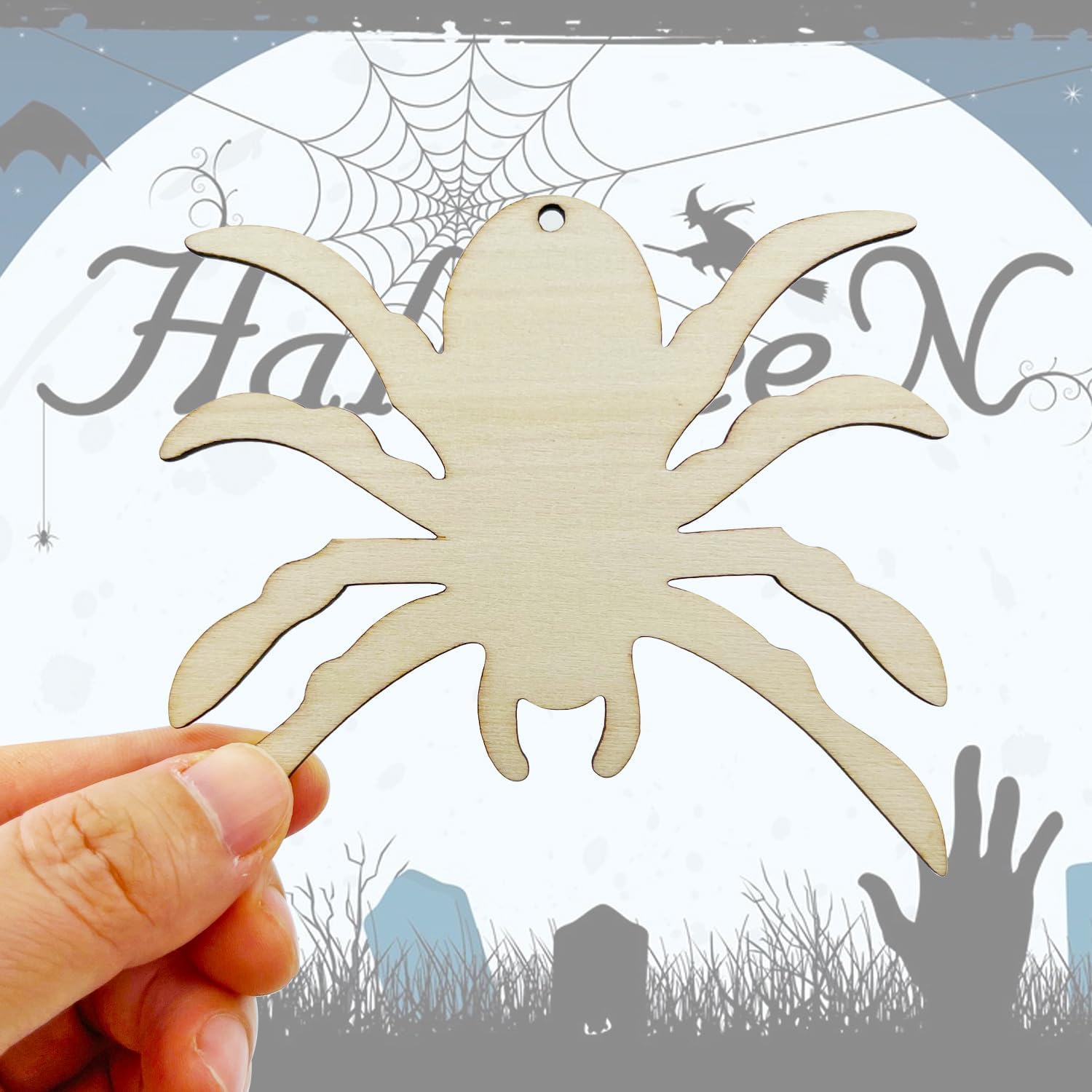Wooden spider decoration held by a hand with Halloween-themed background