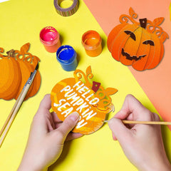 Hands painting a paper pumpkin craft with 'Hello Pumpkin Season' text on a colorful background.